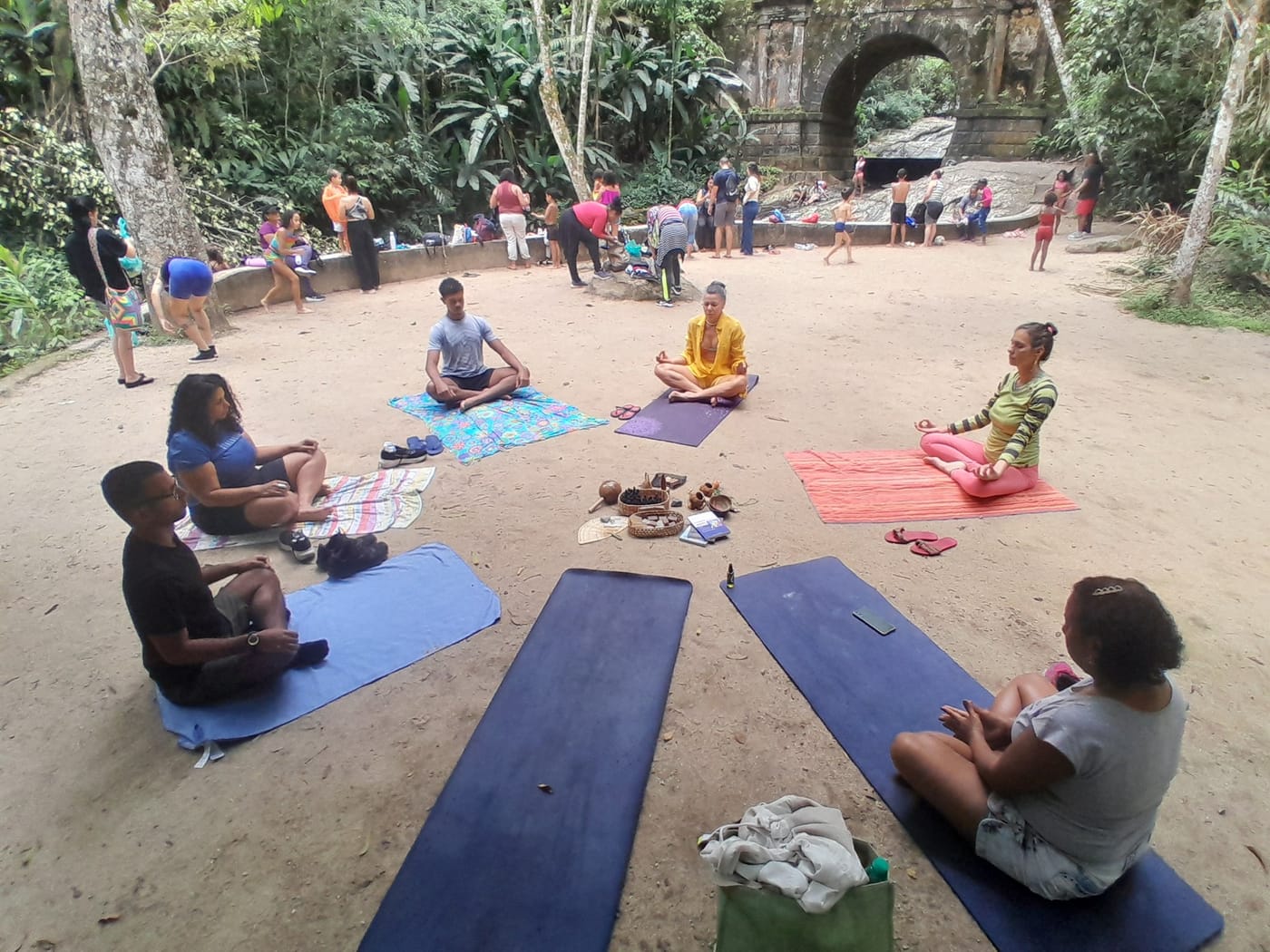 Prática de Kemet Yoga em roda, ao ar livre, com o grupo sentado sobre esteiras