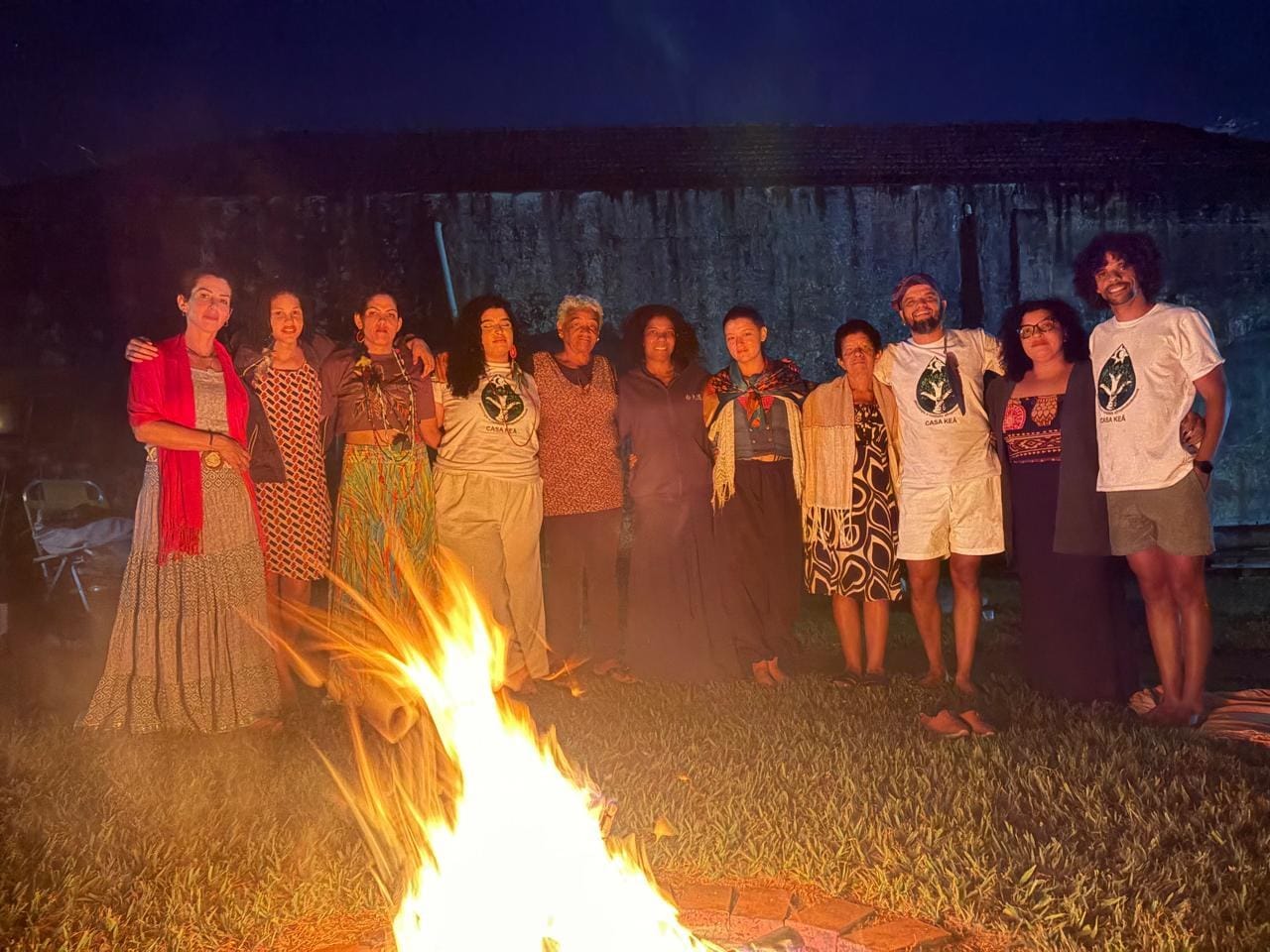 Participantes do Luau reunidos em pé ao redor da fogueira