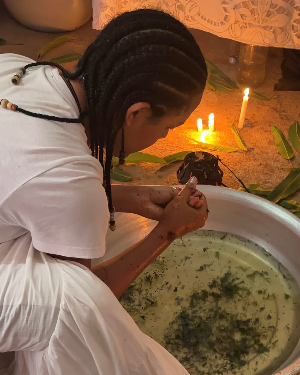 Banho de ervas preparado numa bacia, à luz de velas