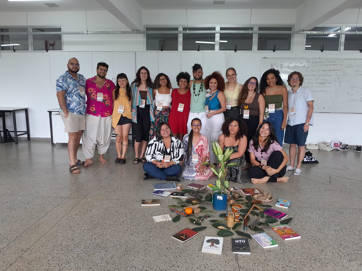 Turma de um processo formativo reunida em sala, em volta de uma roda de livros e plantas