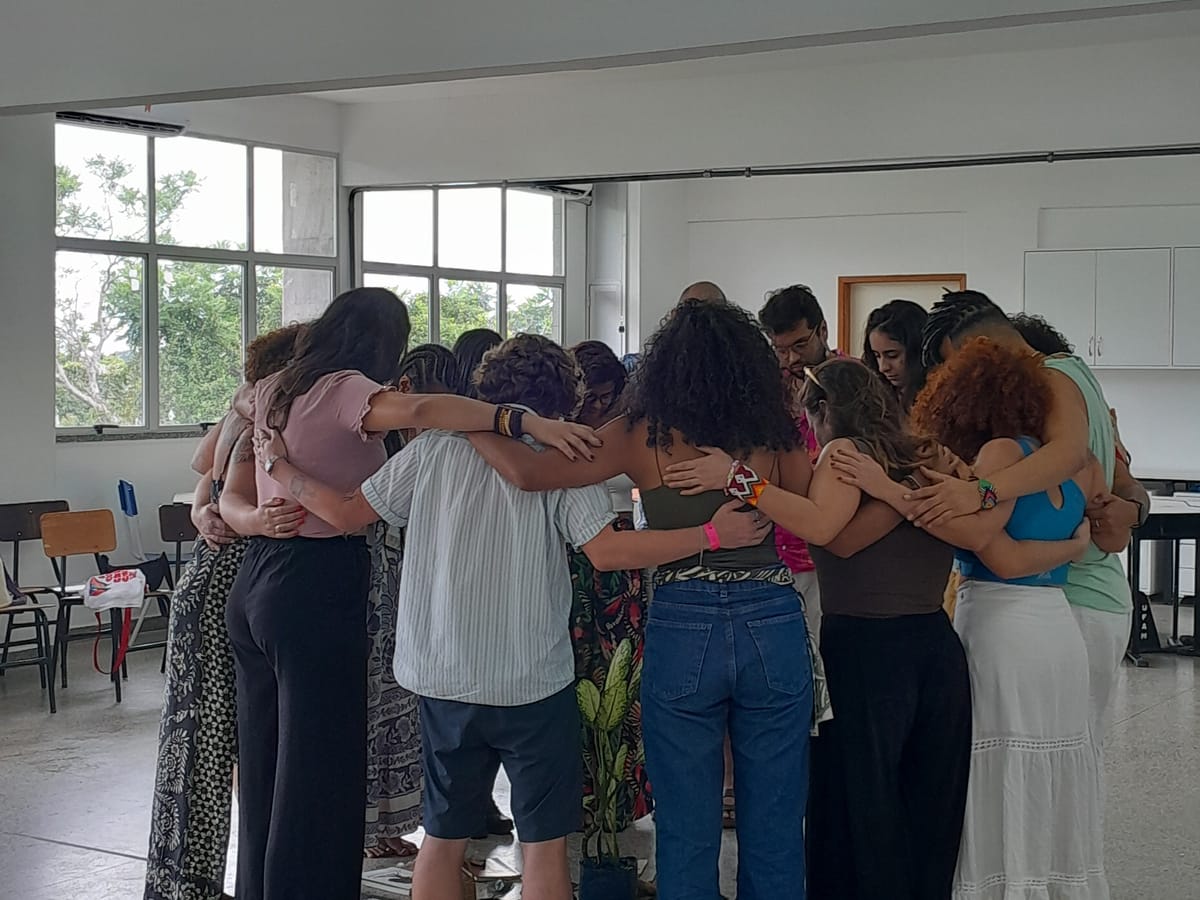 Participantes abraçados em roda no encerramento de um encontro de formação