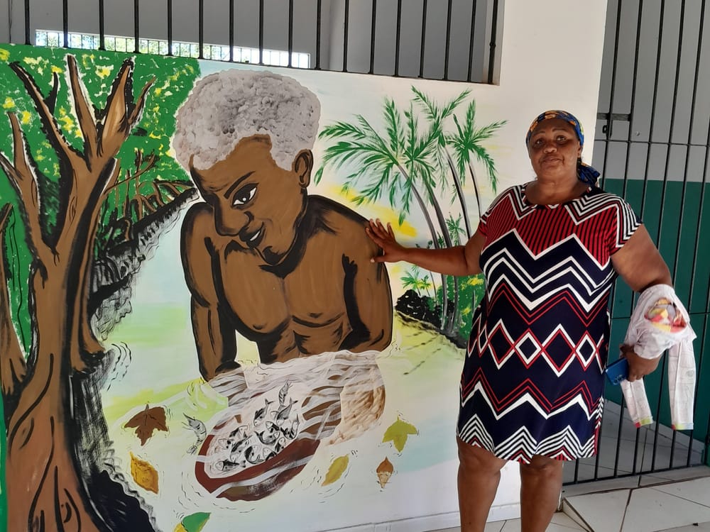 Moradora do Quilombo do Pau Furado ao lado de um mural pintado no Centro de Ciência e Saberes