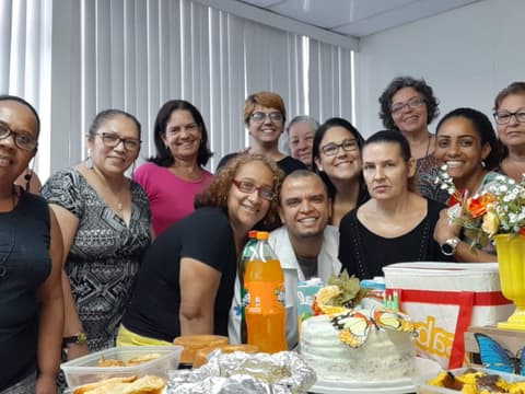 Confraternização de um grupo, com bolo e flores à mesa
