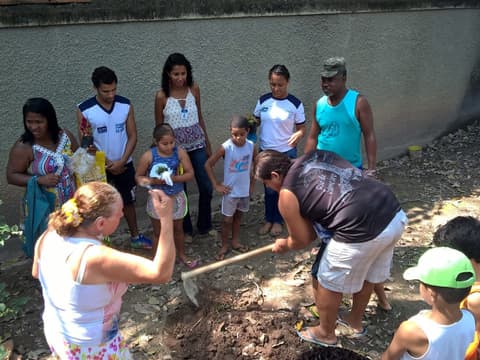 Adultos e crianças cuidando da terra na horta