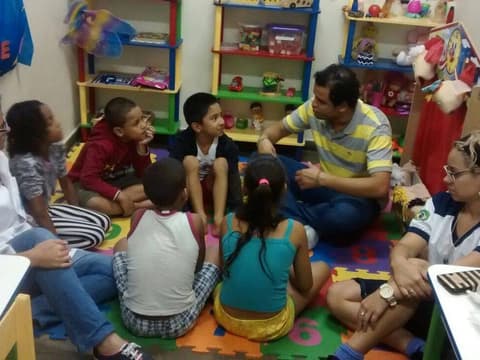 Roda com crianças e profissionais em uma sala de brincar